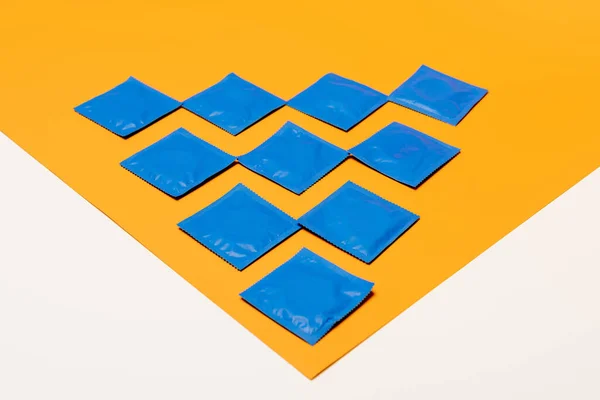 Conditionnements avec préservatifs sur surface orange isolés sur blanc — Photo de stock