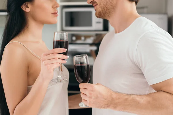 Vista recortada de la pareja sosteniendo vasos con vino tinto durante el autoaislamiento en casa - foto de stock