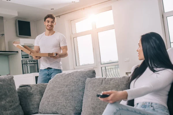Beautiful couple having pizza and watching tv with remote controller during self isolation at home — Stock Photo