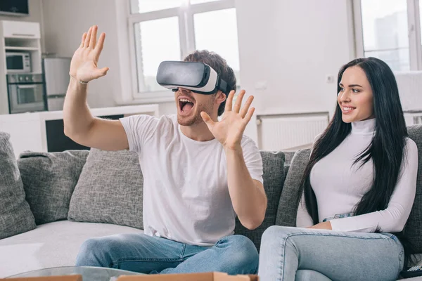 Schöne Frau sieht aufgeregt in Virtual-Reality-Headset während der Selbstisolierung zu Hause — Stockfoto