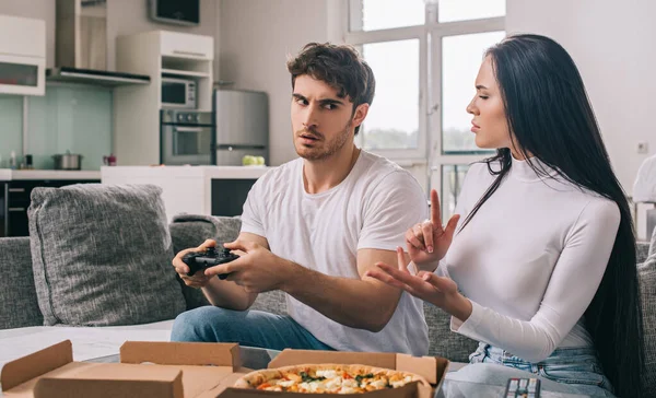 KYIV, UKRAINE - APRIL 16, 2020: beautiful couple with pizza and joystick quarreling during self isolation at home — Stock Photo