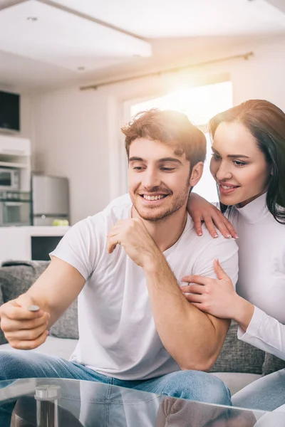 Hermosa pareja lanzando moneda durante el auto aislamiento en casa - foto de stock