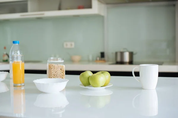 Flocos de milho, maçãs, leite, suco de laranja e xícara de café para o café da manhã na cozinha — Fotografia de Stock