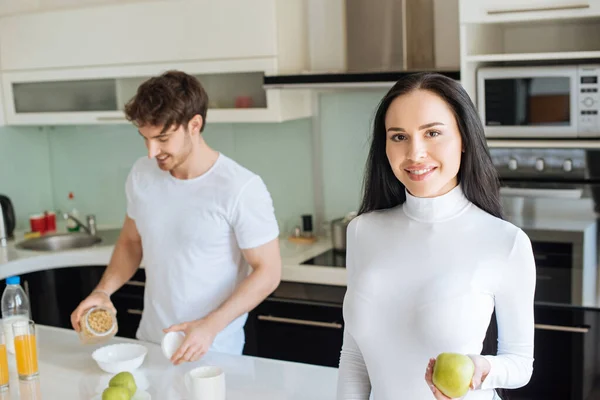 Belo casal tendo flocos de milho e maçãs para o café da manhã durante o auto-isolamento em casa — Fotografia de Stock