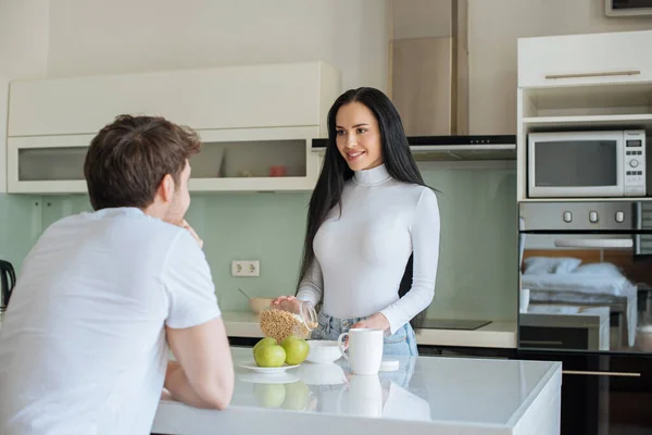 Lächelnde Frau und Mann mit Cornflakes und Äpfeln zum Frühstück während der Selbstisolierung zu Hause — Stockfoto