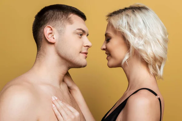 Vue latérale du couple souriant se regardant sur fond jaune — Photo de stock