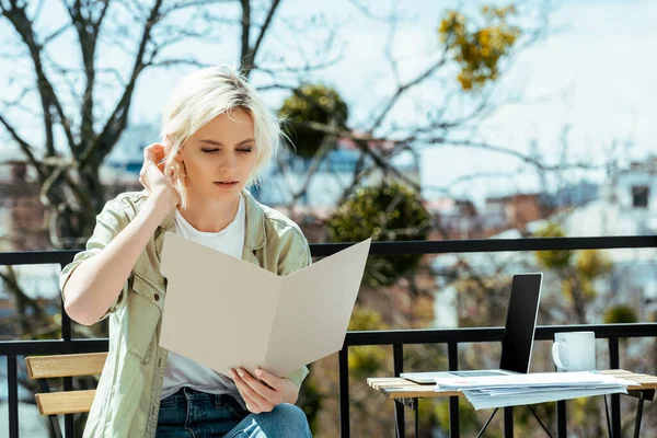 Freelancer sentado no terraço com pasta perto de laptop, bebida e papéis — Fotografia de Stock