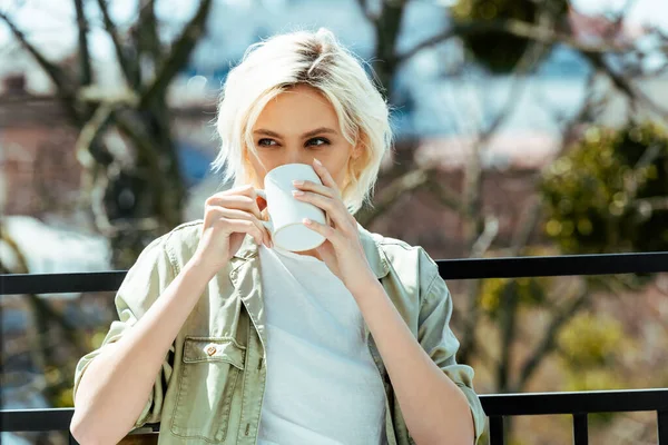 Blonde girl sitting on terrace with mug — Stock Photo