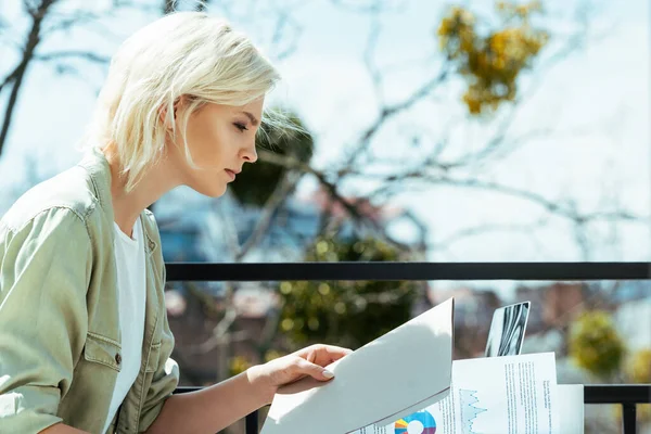 Blonde businesswoman sitting on terrace with folder and papers — Stock Photo