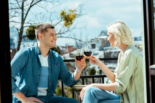 Coppia sorridente clinking con bicchieri di vino sulla terrazza soleggiata — Foto stock