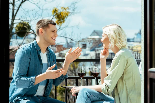 Couple souriant parlant sur la terrasse ensoleillée avec du vin rouge — Photo de stock