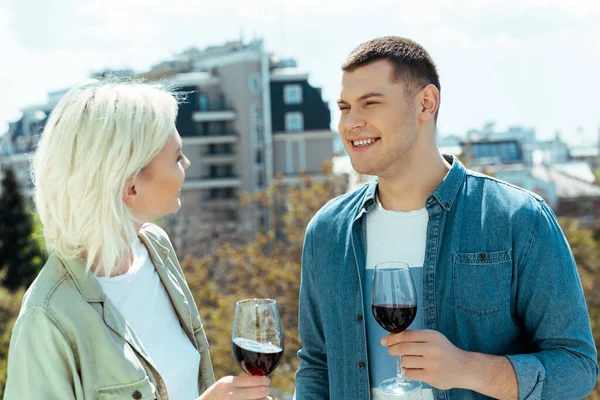 Улыбающаяся пара с красным вином на солнечной террасе — стоковое фото