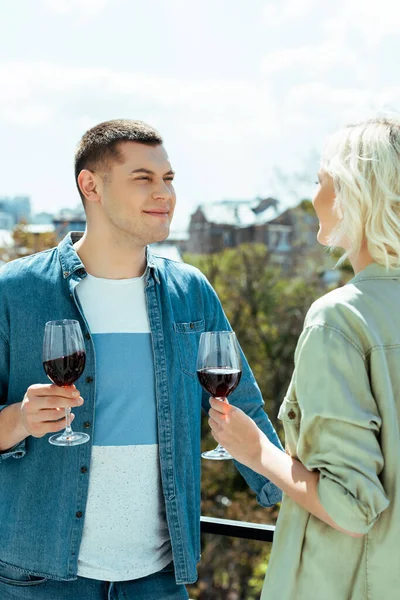 Coppia sorridente con vino rosso sulla terrazza soleggiata — Foto stock