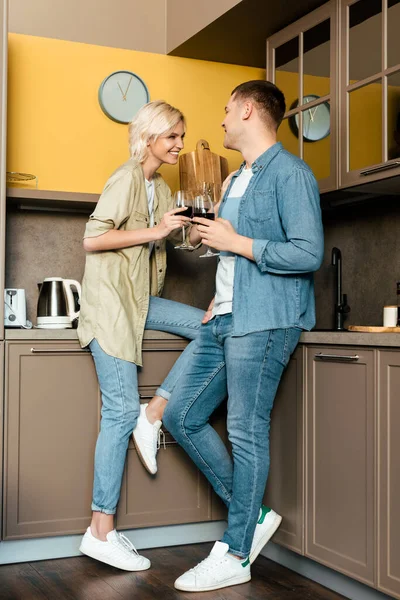 Coppia sorridente bere vino rosso insieme in cucina — Foto stock