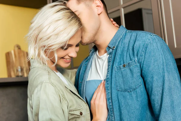 Sonriente joven pareja cariñosa abrazos y besos en casa - foto de stock