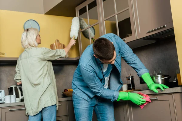 Pareja haciendo limpieza de la casa durante la cuarentena en la cocina en casa - foto de stock
