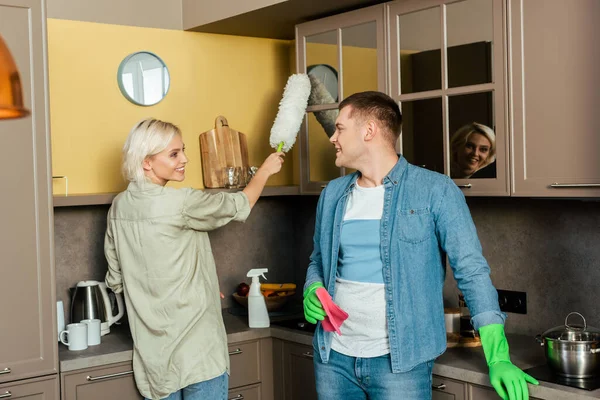 Coppia sorridente facendo pulizia della casa durante la quarantena in cucina a casa — Foto stock