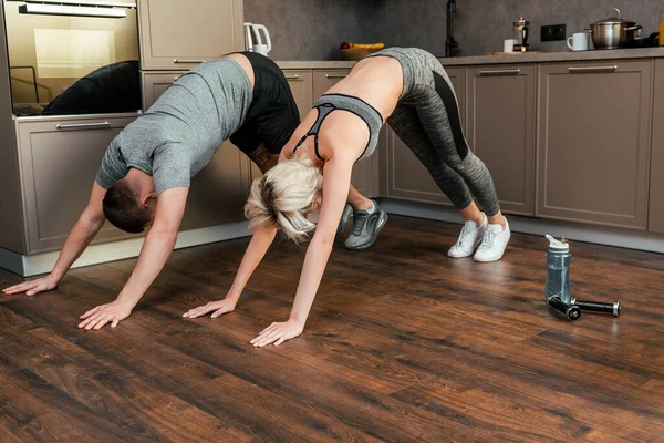 Pareja joven haciendo ejercicio juntos en casa durante la cuarentena - foto de stock