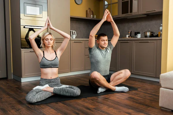 Young couple practicing yoga together in lotus pose at home during quarantine — Stock Photo