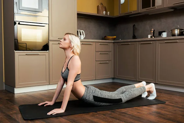 Blonde jeune femme étirant à la maison pendant la quarantaine — Photo de stock