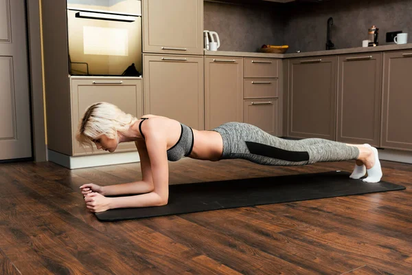 Blonde young woman doing plank at home during quarantine — Stock Photo