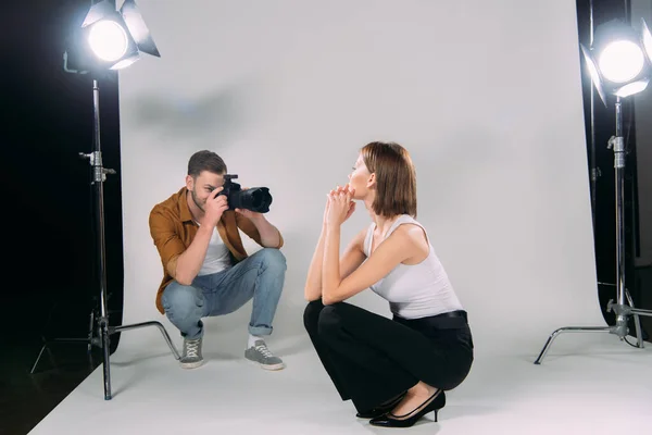 Fotógrafo tomando fotos de modelo atractivo en estudio fotográfico - foto de stock