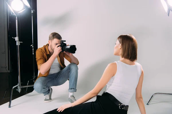 Modelo posando enquanto fotógrafo tirar foto na câmera digital no estúdio de fotos — Fotografia de Stock