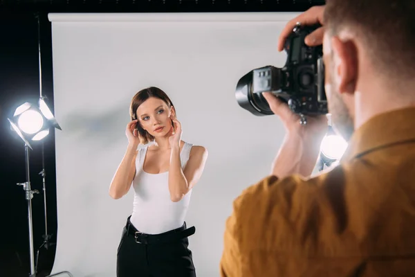 Foco seletivo de modelo atraente posando no fotógrafo com câmera digital no estúdio de fotos — Fotografia de Stock