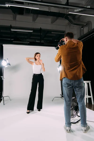 Fotógrafo trabalhando com modelo jovem atraente no estúdio de fotografia — Fotografia de Stock