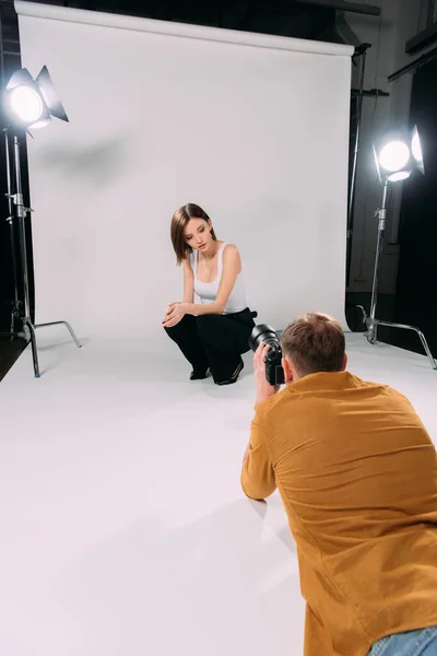 Attractive model posing while working with photographer in photo studio — Stock Photo