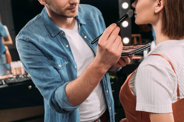 Vista recortada do artista de maquiagem aplicando blush no modelo no estúdio de fotografia — Fotografia de Stock