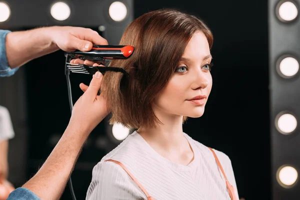 Makeup artist using curling iron on attractive model in photo studio — Stock Photo