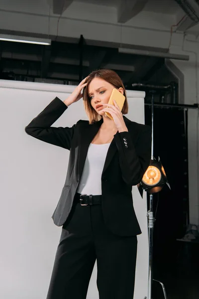 Upset elegant model talking on smartphone in photo studio — Stock Photo