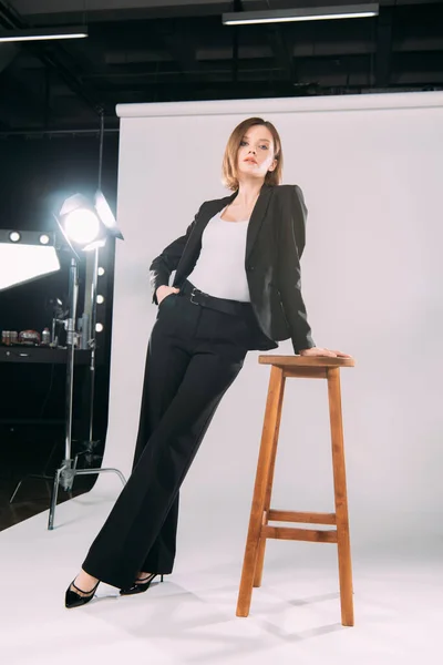 Low angle view of elegant model posing near chair i photo studio — Stock Photo