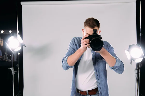 Photographer taking photo with digital camera in photo studio — Stock Photo