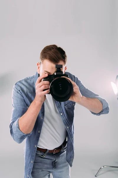 Photographer taking picture with digital camera near floodlight in photo studio — Stock Photo