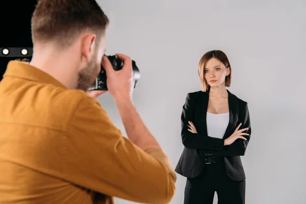 Selective focus of elegant model posing at photographer with digital camera in photo studio — Stock Photo