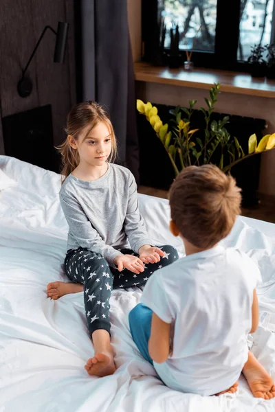 Messa a fuoco selettiva del bambino guardando il fratello mentre si siede sul letto — Foto stock