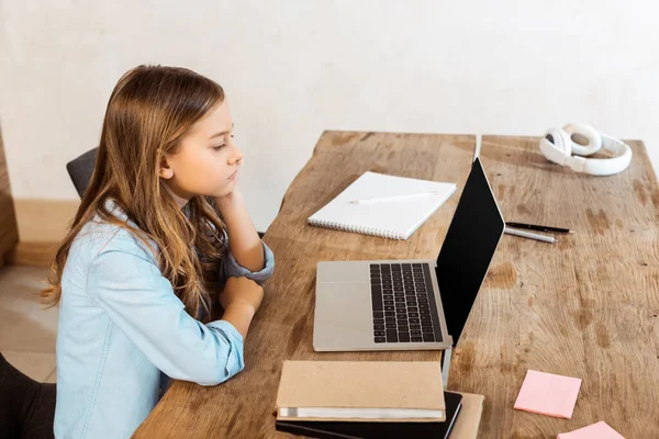 Seitenansicht des Kindes, das beim Online-Lernen zu Hause auf Laptop mit leerem Bildschirm schaut — Stockfoto