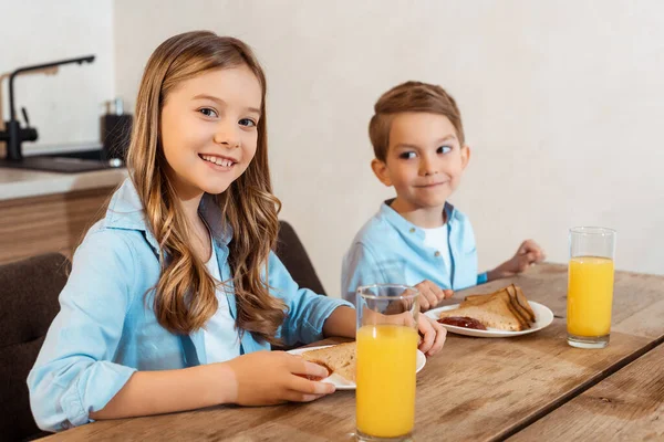 Selektiver Fokus des glücklichen Kindes, das in der Nähe des Bruders lächelt und leckeres Frühstück — Stockfoto