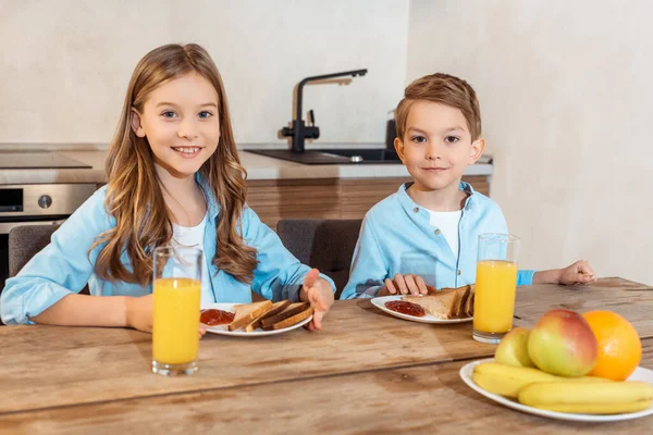 Selective focus of happy siblings smiling near tasty breakfast — Stock Photo