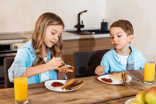 Selective focus of kid making toast with jam near brother at home — Stock Photo