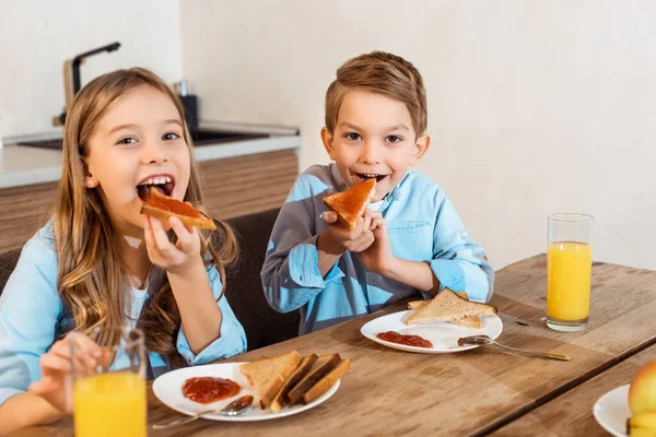 Selective focus of happy siblings eating toast bread with bread — Stock Photo