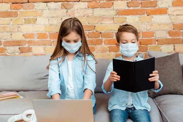 Siblings in medical masks e-learning at home — Stock Photo