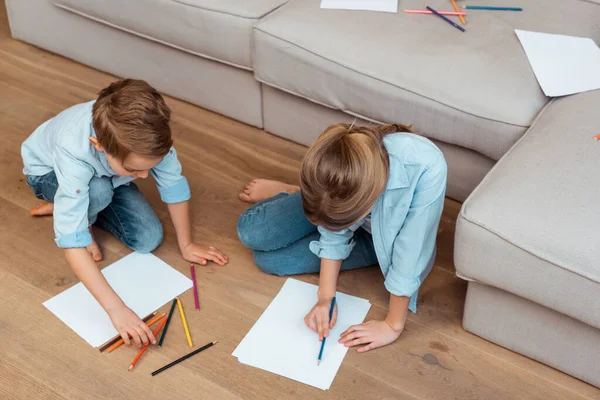 Schwester und Bruder sitzen auf dem Boden und zeichnen im Wohnzimmer — Stockfoto