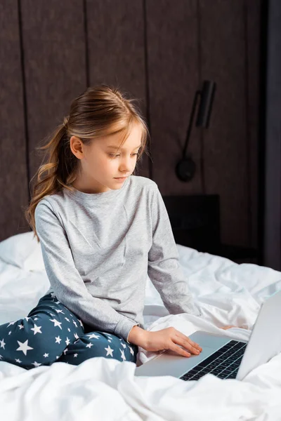 Niño usando el ordenador portátil con e-learning en el dormitorio - foto de stock