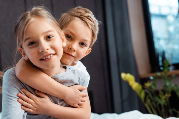 Cute brother hugging happy sister at home — Stock Photo