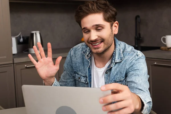 Focus sélectif de sourire pigiste ayant chat vidéo sur ordinateur portable dans la cuisine — Photo de stock