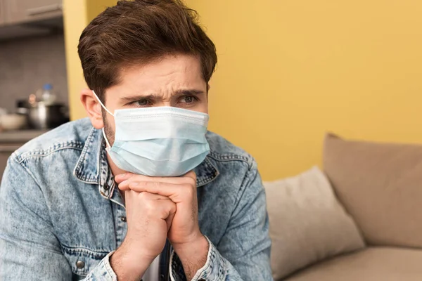 Pensif homme en masque médical regardant loin à la maison — Photo de stock