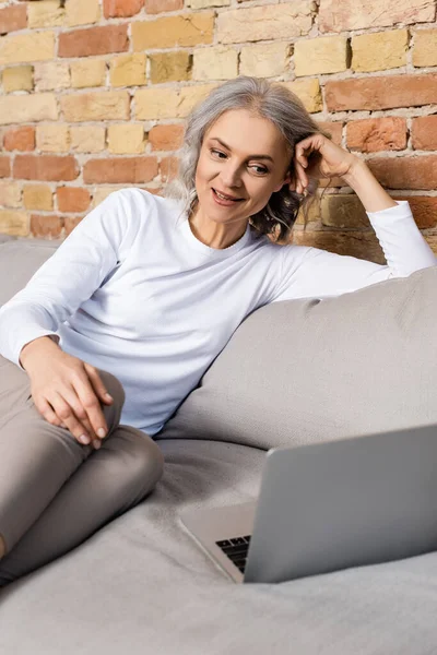 Cheerful and mature woman watching movie on laptop — Stock Photo